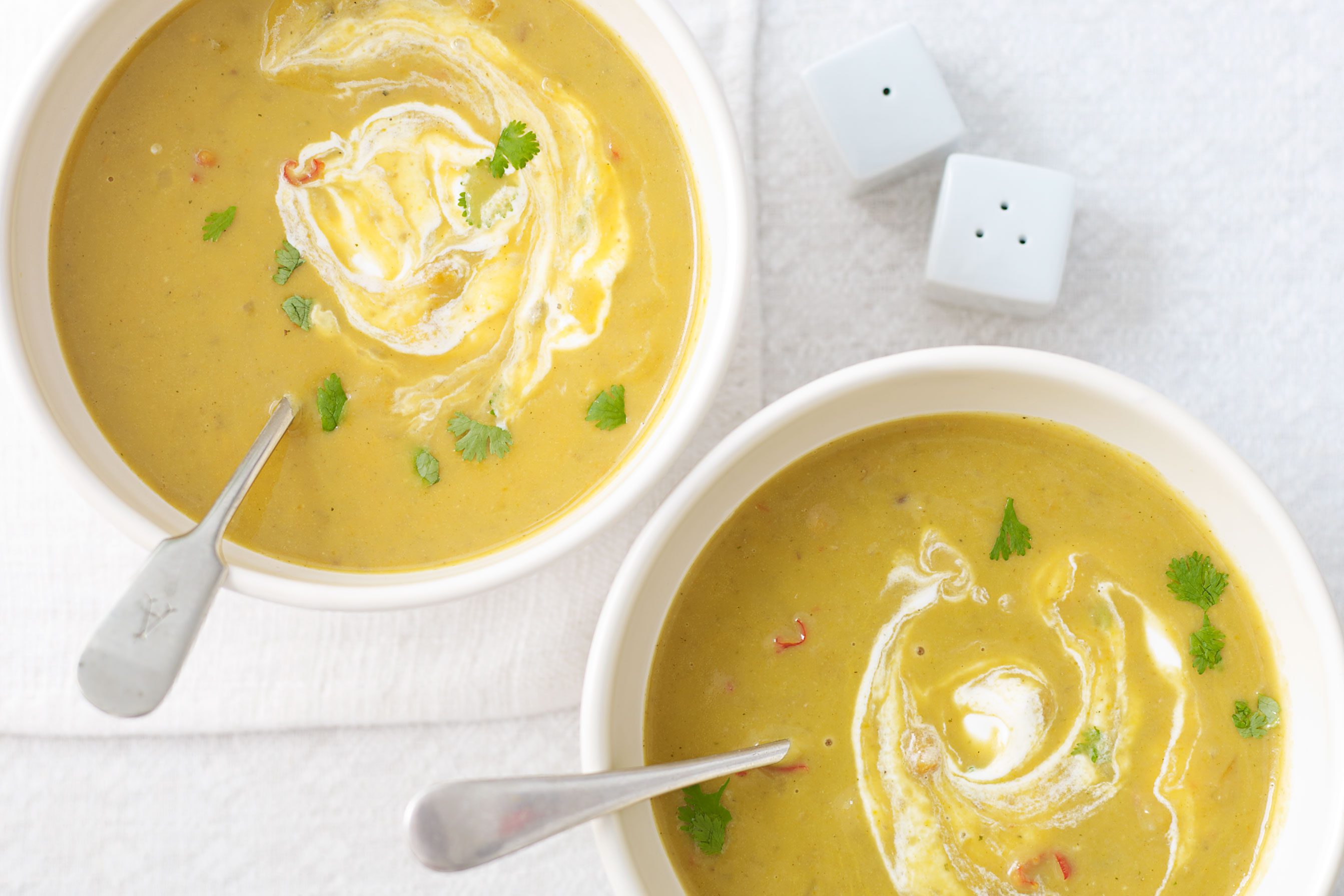 Two bowls of spiced root vegetable soup topped with cream