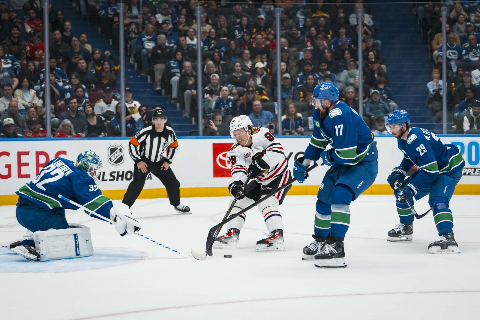 Nov 5, 2025; Vancouver, British Columbia, CAN; Vancouver Canucks goalie Kevin Lankinen (32) and defenseman Marcus Pettersson (29) watch as defenseman Filip Hronek (17) stick checks Chicago Blackhawks forward Connor Bedard (98) in the first period at Rogers Arena. Mandatory Credit: Bob Frid-Imagn Images