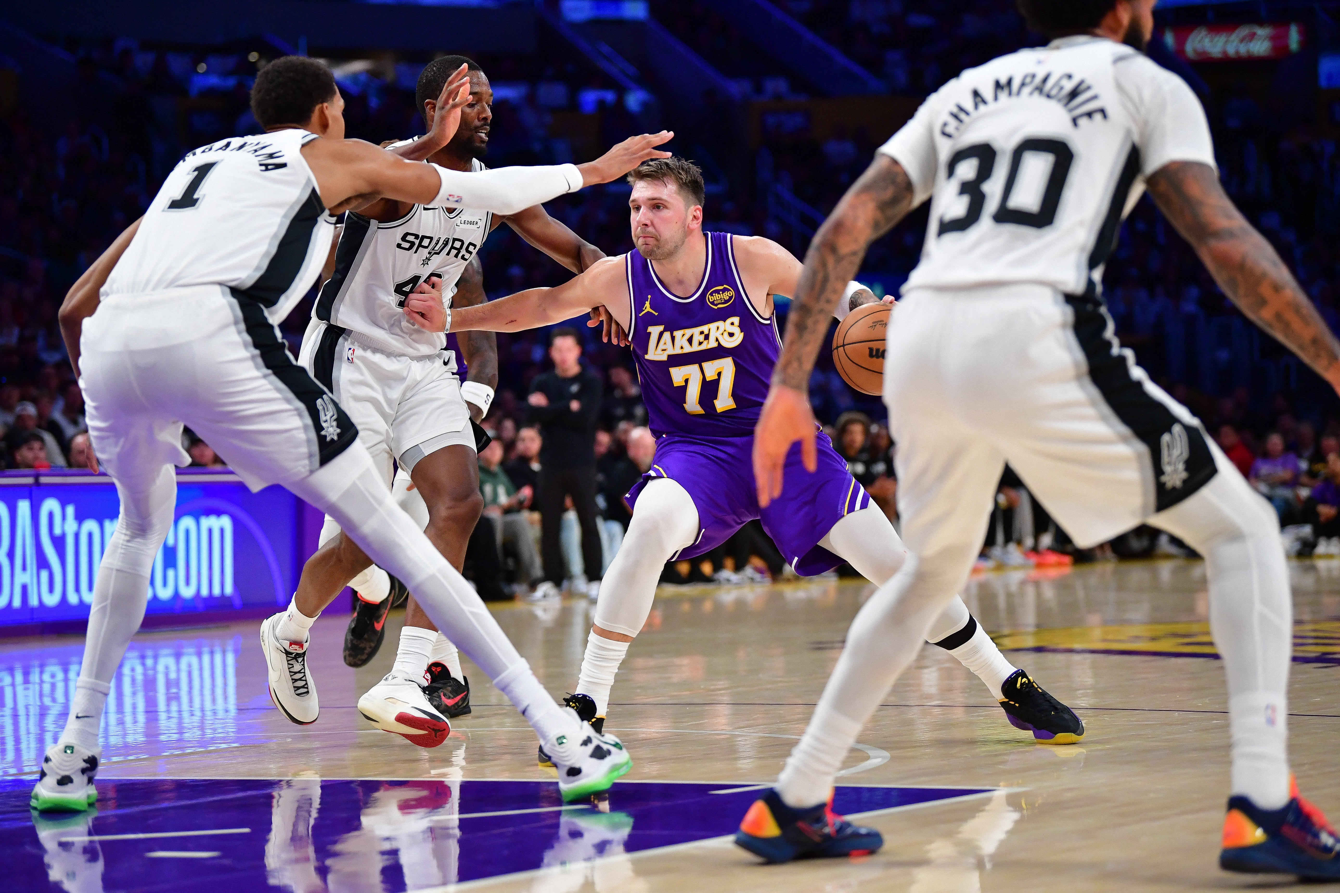Nov 5, 2025; Los Angeles, California, USA; Los Angeles Lakers guard Luka Doncic (77) moves to the basket against San Antonio Spurs forward Victor Wembanyama (1) forward Harrison Barnes (40) and forward Julian Champagnie (30) during the first half at Crypto.com Arena. Mandatory Credit: Gary A. Vasquez-Imagn Images
